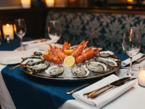 Chilled platter met oesters en langoustines op een elegant gedekte restauranttafel met kaarslicht en kristallen wijnglazen.